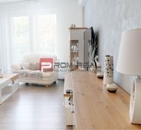 Living room in a two-room apartment with a wooden decor floor and white furniture.