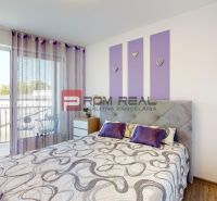 Bedroom in a two-room apartment with a bed, wardrobe, and purple decorations.