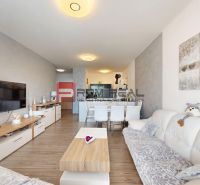 Living room in a two-room apartment with white furniture and a wooden decor floor.