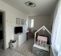 Children's room in a three-room apartment with wood-patterned flooring and decorative wallpaper.