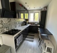 A kitchen with mosaic tiles and a wooden decor floor in a 3-room apartment.