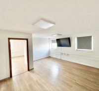 The interior of offices with wood-patterned flooring and a television on the wall.