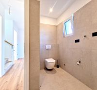 A toilet in a 3-room apartment with a minimalist design and a wooden decor floor.