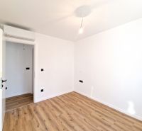 A room with white walls and a wood-decorated floor in a 3-room apartment.