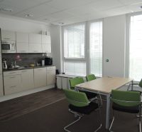 Offices with a kitchenette, wooden decor flooring, and green chairs.