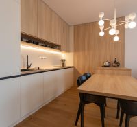 A kitchen in a 2-room apartment with a wooden decor floor and a dining table.