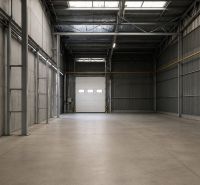 Spacious warehouse interior with concrete floor and large doors.