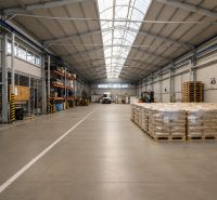 Interior of warehouses and halls with stacked pallets and a handling cart on the floor.
