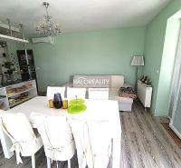 Bright living space with a dining table and wood-patterned flooring in a three-room apartment.
