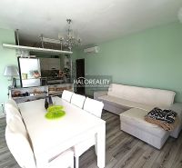 Living room in a three-room apartment with white furniture and a wooden decor floor.