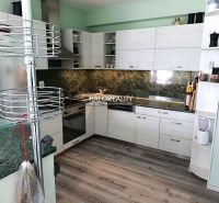 A kitchen in a 3-room apartment with a wooden decor floor and green tiles.
