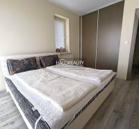 A bedroom in a three-room apartment with a wooden decor floor and a built-in wardrobe.