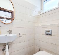 A bathroom with a round mirror and beige tiles in a family house.