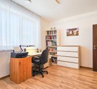 A workspace with a desk, bookshelf, and wooden decor flooring in a family house.