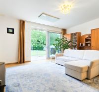 Living room in a family house with wood-patterned flooring and sliding doors to the terrace.