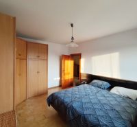 Bedroom in a two-room apartment with a bed, wardrobe, and wooden decor flooring.