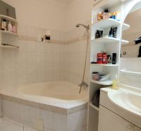 Bathroom in a 2-room apartment with tiles, a bathtub, and storage space.