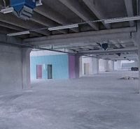A vast empty space in warehouses and halls with concrete columns and a colorful wall.