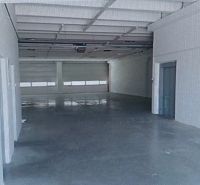 A spacious interior of a warehouse and hall with a concrete floor and white walls.