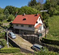 A family house on a sloped plot surrounded by greenery with an access road in Banky.