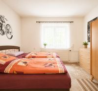A bedroom in a family house with a double bed, a dresser, and a motorcycle motif on the wall.