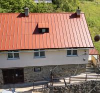 A family house in Banky with a red metal roof and a stone foundation.