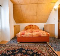 A bedroom in a family house with wooden paneling and a patterned carpet.