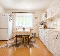 A kitchen in a family house with a kitchen unit, dining table, and floor decor.