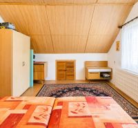 A bedroom in a family house with carpet decor and a slanted wooden ceiling.