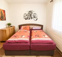 A bedroom in a family house with a motorcycle decoration above the bed and wooden furniture.
