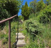 Stone stairs in the garden of a family house in Banky, surrounded by greenery and trees.