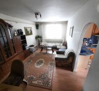 Living room with a sofa, antique cabinet, and wooden decor flooring in a family house.