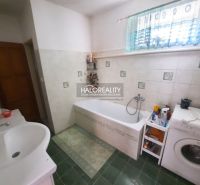 A bathroom in a family house with green tiles, a bathtub, and a washing machine.