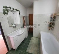 A bathroom with a bathtub and a white sink in a family house, green tiles.