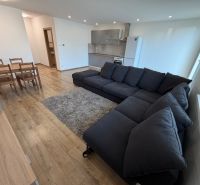 Living room with a dark sofa, dining table, and wooden decor flooring.