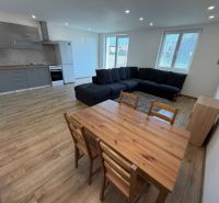 Living room with kitchen in a 3-room apartment with a wooden decor floor and a large sofa.