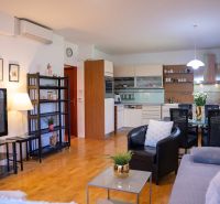 Living room in a 3-room apartment with a wooden decor floor, kitchenette, and dining table.