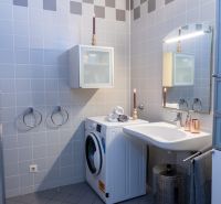 A bathroom with a washing machine, a sink, and gray tiles in a 3-room apartment.