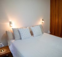 A bedroom in a 3-room apartment with a bed, pillows, and a wooden wardrobe.