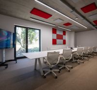 Modern meeting room with a large table, comfortable chairs, and audiovisual equipment.