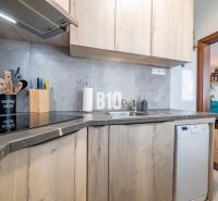 A kitchen with a wooden decor in a studio apartment, open transition to the living room.