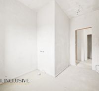 Interior of a 3-room apartment with white walls and an opening to another room.