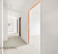 A hallway in a 3-room apartment with white walls and unfinished doors.