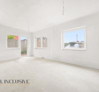 A spacious room with large windows in a 3-room apartment, white walls, unfinished floor.