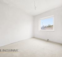 An empty room with a carpet and a large window in a 3-room apartment.
