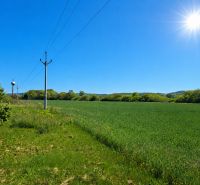 Záhorce, Land - residential: Green field with electric poles and surrounding forest.