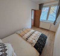Bedroom with wood-patterned flooring in a 2-room apartment, bed and window with blinds.