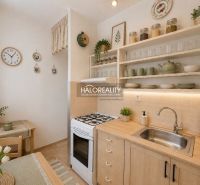 A kitchen with a gas stove, decorated shelves, and a dining table in a two-room apartment.