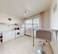 The kitchen of a two-room apartment with a wooden decor floor, white furniture, and a bar counter.