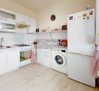A kitchen in a 2-room apartment with white cabinets and a washing machine. Floor with wood decor.